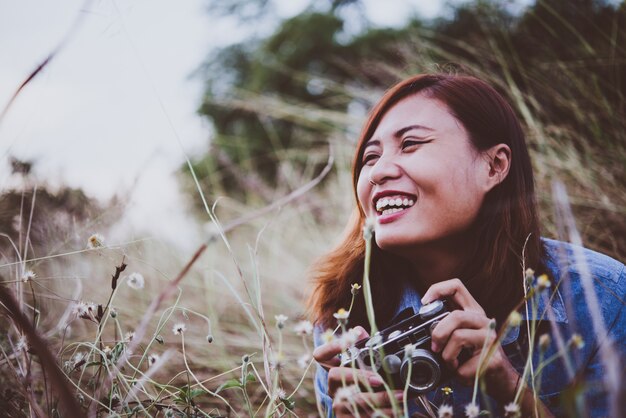 mujer inconformista joven que hace fotos con la cámara de película de época en el campo de verano. Las mujeres concepto de estilo de vida.