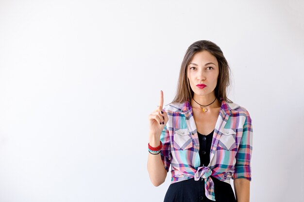 La mujer inconformista tiene una idea apuntando un dedo hacia arriba