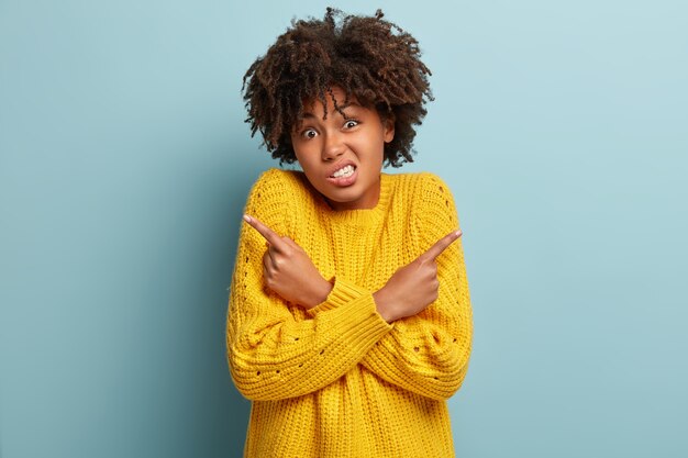 Mujer inconsciente confundida con un afro posando en un suéter rosa