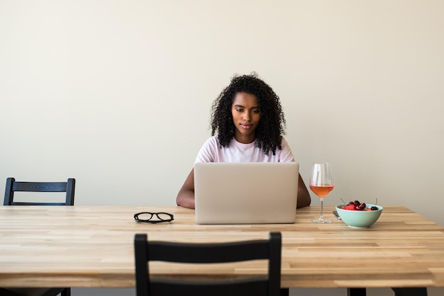 Mujer independiente afroamericana usando laptop en casa