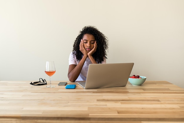 Mujer independiente afroamericana usando laptop en casa