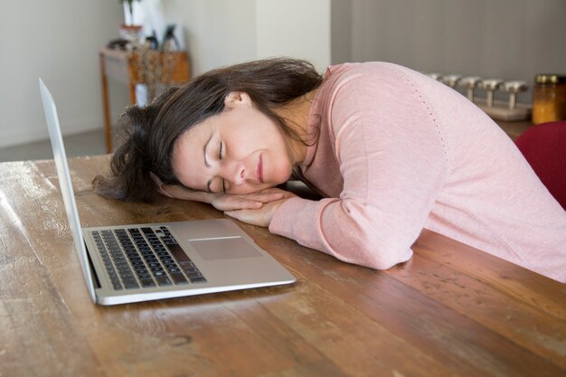 Mujer independiente cansada que duerme en la tabla