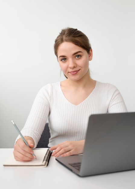 Foto gratuita mujer independiente en escritorio escribiendo en agenda