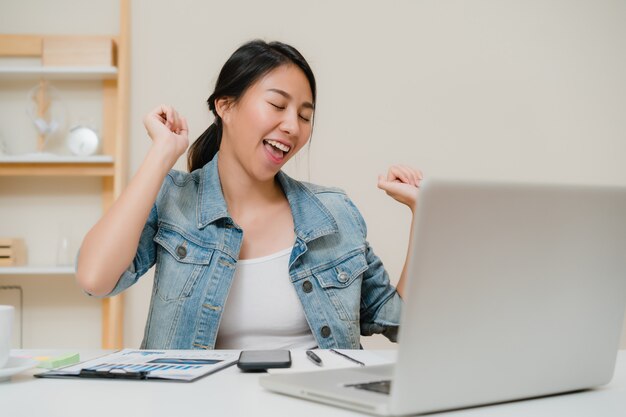 Mujer independiente del negocio que estira su cuerpo porque se siente cansada después de trabajar en el ordenador portátil, hembra elegante que trabaja en casa.