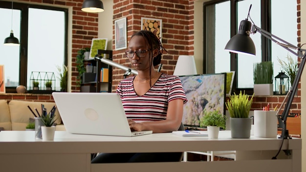 Mujer independiente que trabaja en una computadora portátil para enviar correos electrónicos de forma remota desde su casa, usando una conexión de red en línea. Empresaria haciendo trabajo remoto en la computadora, sentada en el escritorio. Trabajo independiente.