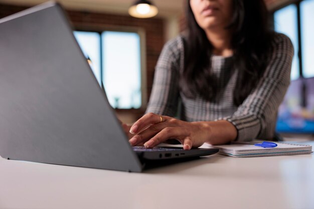 Mujer independiente trabajando en un informe en casa, escribiendo información de investigación en una computadora portátil y navegando por el sitio web de Internet. Búsqueda de datos para crear informes profesionales y enviar correos electrónicos. De cerca.