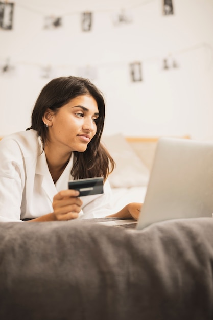 Foto gratuita mujer india trabajando en una computadora portátil y sosteniendo una tarjeta