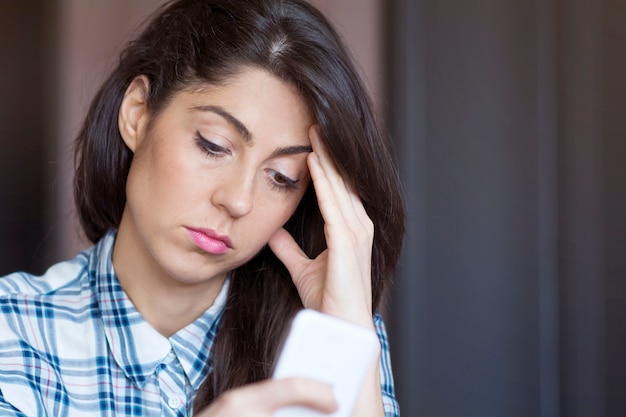 Mujer infeliz mirando su teléfono