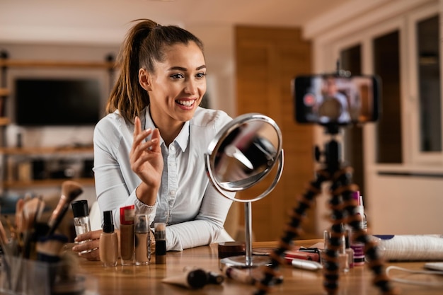 Mujer influyente sonriente hablando de productos de belleza mientras vloguea desde casa