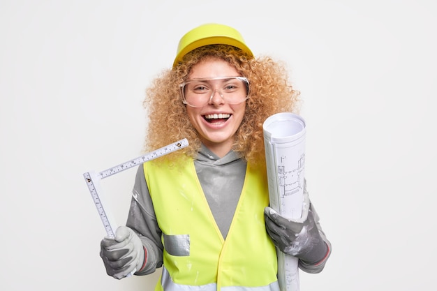 Mujer ingeniera de construcción tiene proyecto arquitectónico y cinta métrica feliz de terminar de dibujar planos viste uniforme de casco protector