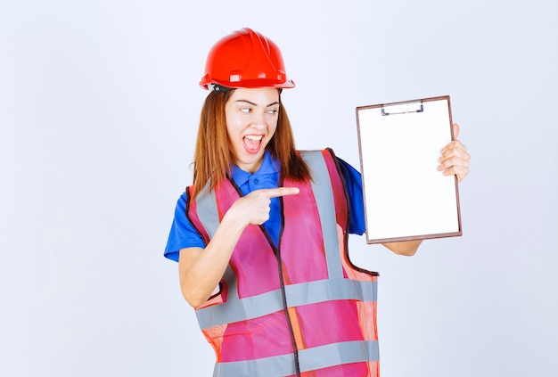 Mujer ingeniera en uniforme sosteniendo un archivo de informes en blanco.