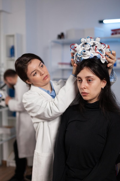 Mujer de ingeniero investigador poniendo escáner eeg en la cabeza del paciente de la mujer durante el experimento de neurología en el laboratorio médico. Médico neurólogo analizando la evolución del cerebro monitoreando la actividad del sistema nervioso