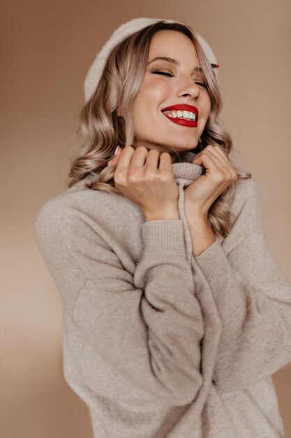 Mujer inspirada en acogedor suéter marrón posando con los ojos cerrados