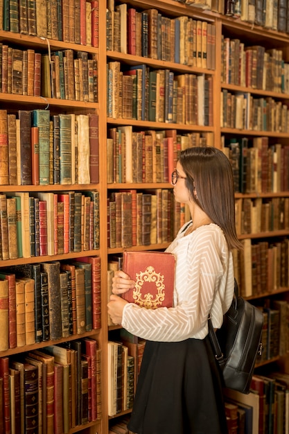 Mujer inteligente con libro en biblioteca