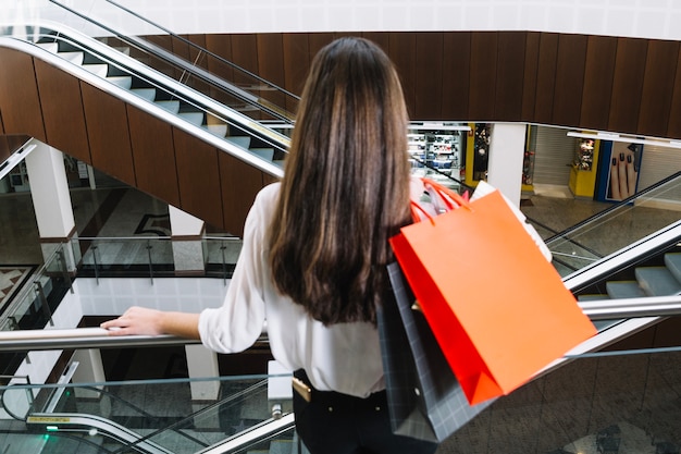 Mujer irreconocible con bolsas en el centro comercial