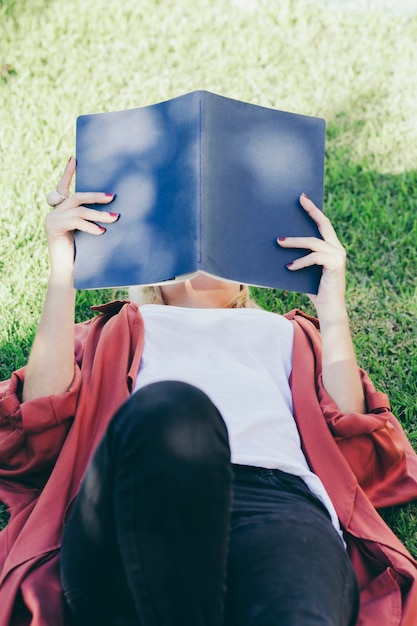 Mujer irreconocible leyendo sobre hierba