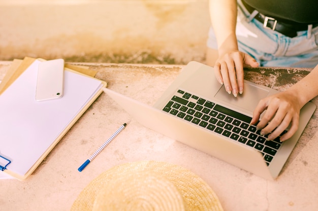 Mujer irreconocible navegando por internet en su computadora portátil en el lugar de trabajo