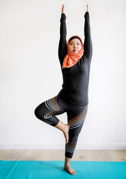 Mujer islámica haciendo yoga en la habitación