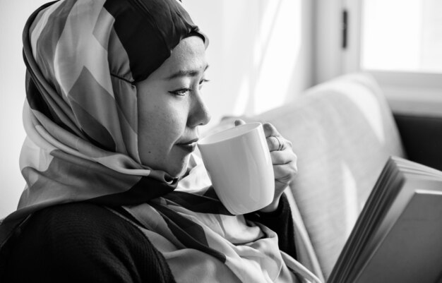 Mujer islámica leyendo y bebiendo café