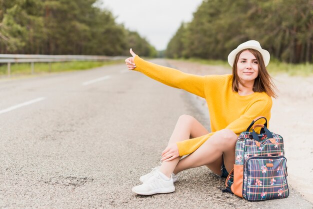 Mujer itinerante haciendo autostop y sentada