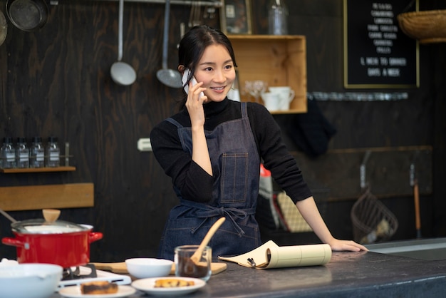 Mujer japonesa hablando por teléfono inteligente en un restaurante