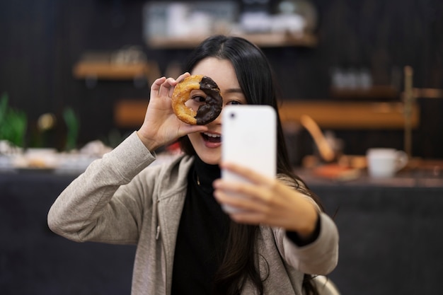 Mujer japonesa tomando selfie con donut