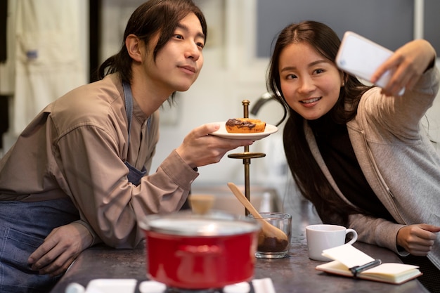 Mujer japonesa tomando selfie con hombre y donut en un restaurante