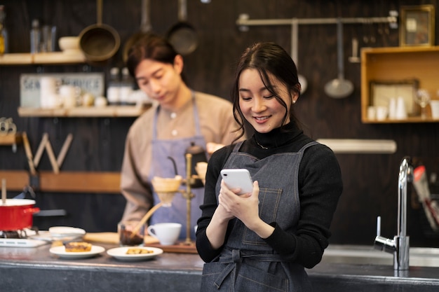 Mujer japonesa usando su teléfono inteligente en un restaurante