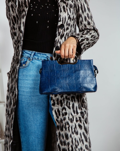 Mujer en jeans, top negro y cárdigan con estampado de leopardo con bolso azul marino