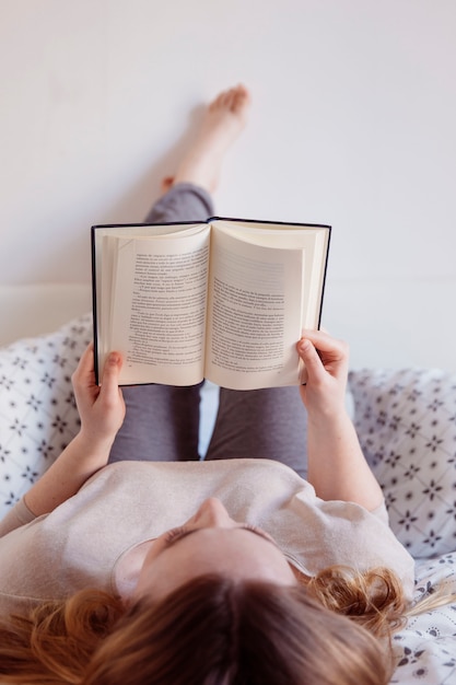 Mujer de jengibre leyendo en la cama