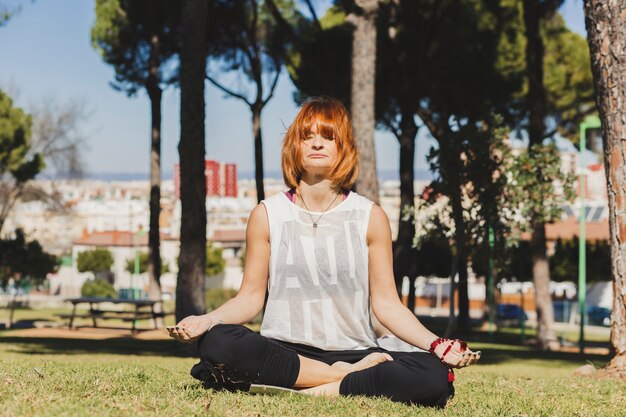 Mujer de jengibre meditando en el parque