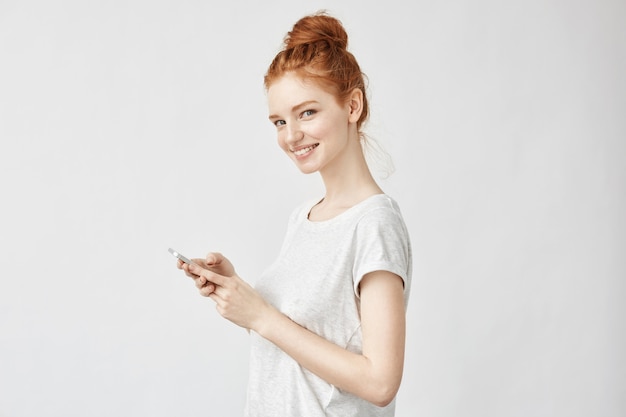 mujer de jengibre sonriendo sosteniendo el teléfono.