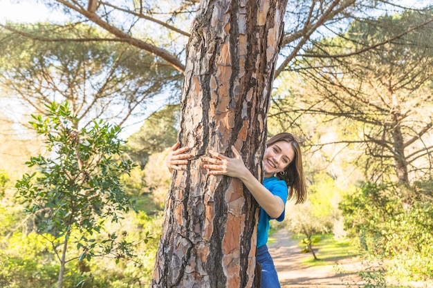 Mujer joven abrazando el árbol en el bosque