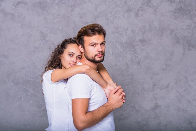 Mujer joven abrazando a hombre por detrás