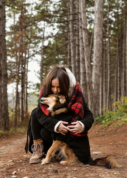 Mujer joven abrazando a su perro en el bosque