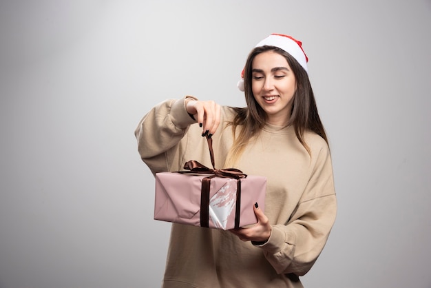 Mujer joven abriendo una caja de regalo de Navidad.