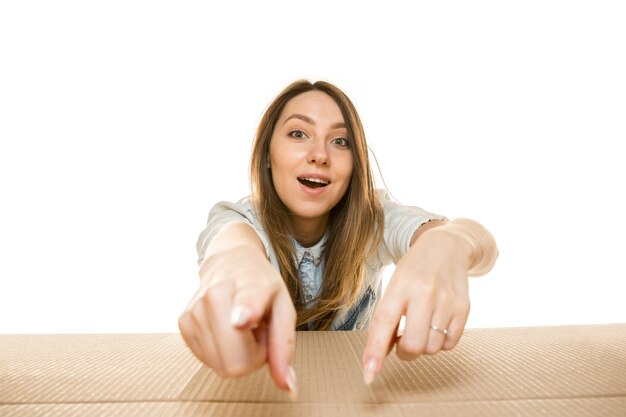 Mujer joven abriendo el paquete postal más grande aislado en blanco