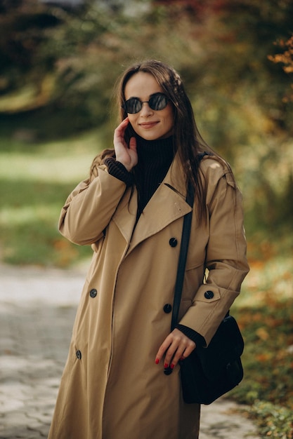 Mujer joven en abrigo beige caminando en el parque