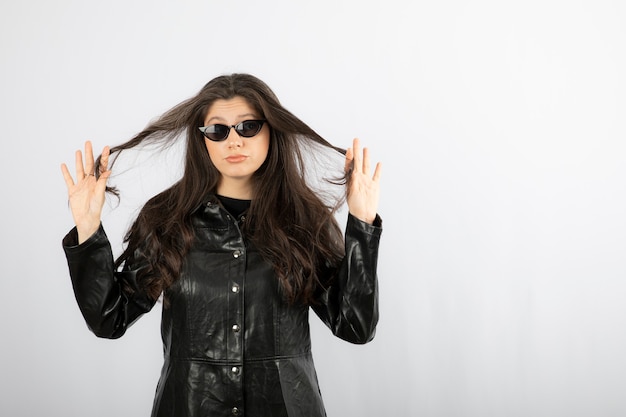 mujer joven en abrigo negro con gafas y posando.