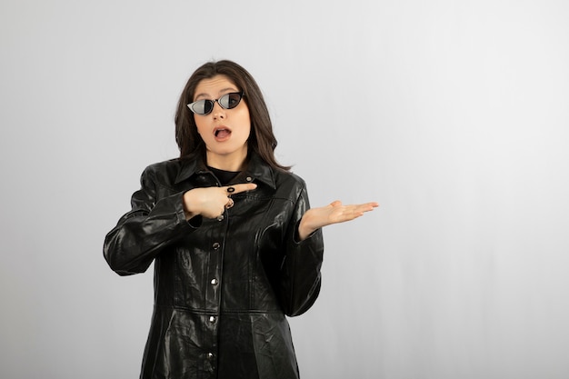 mujer joven en abrigo negro con gafas y posando.