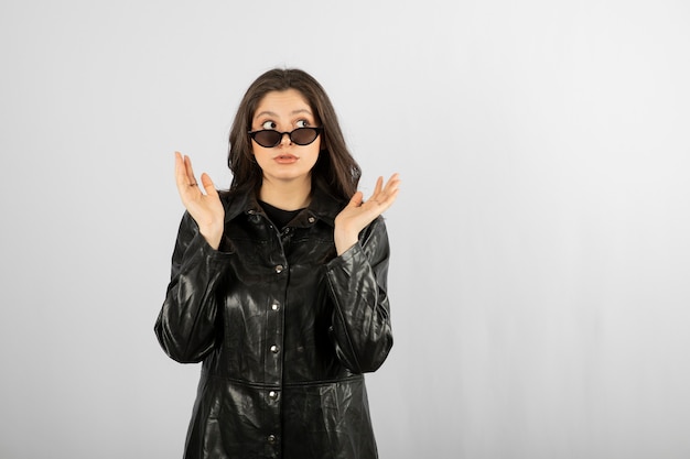 mujer joven en abrigo negro con gafas y posando.