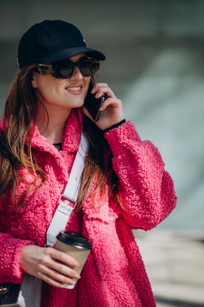 Mujer joven en abrigo rosa de pie en la calle