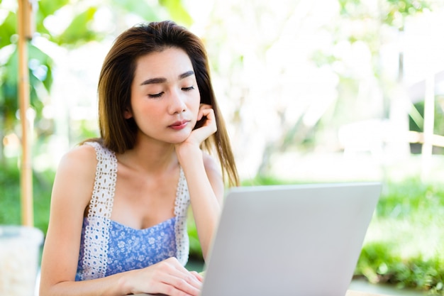 Mujer joven aburrida mientras uso portátil