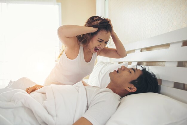 Mujer joven aburrida con su novio roncando