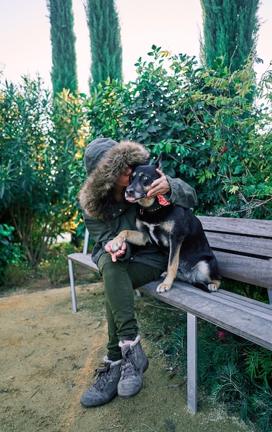 Mujer joven acaricia a su perro en el parque al atardecer. Concepto de amistad, felicidad, compañía.