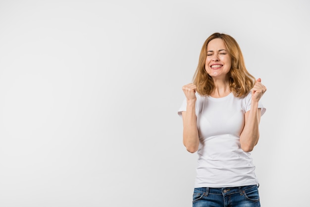 Foto gratuita mujer joven acertada que anima después de ganar contra el contexto blanco