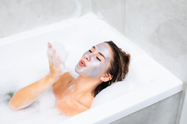 Mujer joven, acostado, en, bañera, con, un, hoja, mascarilla, en, ella, cara