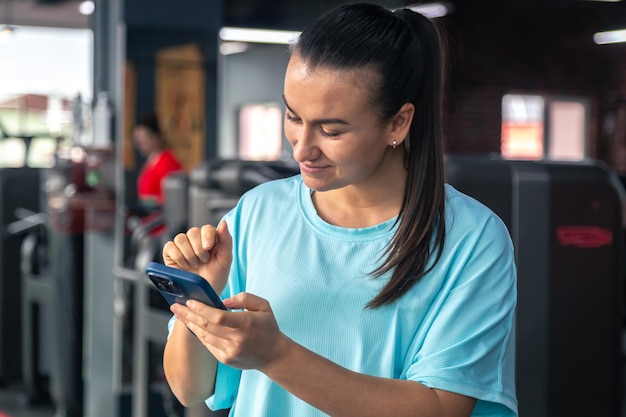 Foto gratuita mujer joven activa usando teléfono inteligente en el gimnasio