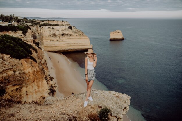 Mujer joven admirando una vista impresionante mientras está de pie en el borde de la cima de la montaña