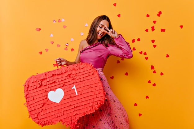 Foto gratuita mujer joven adorable en blusa rosa bailando con felicidad. filmación en interiores de impresionante blogger sonriendo